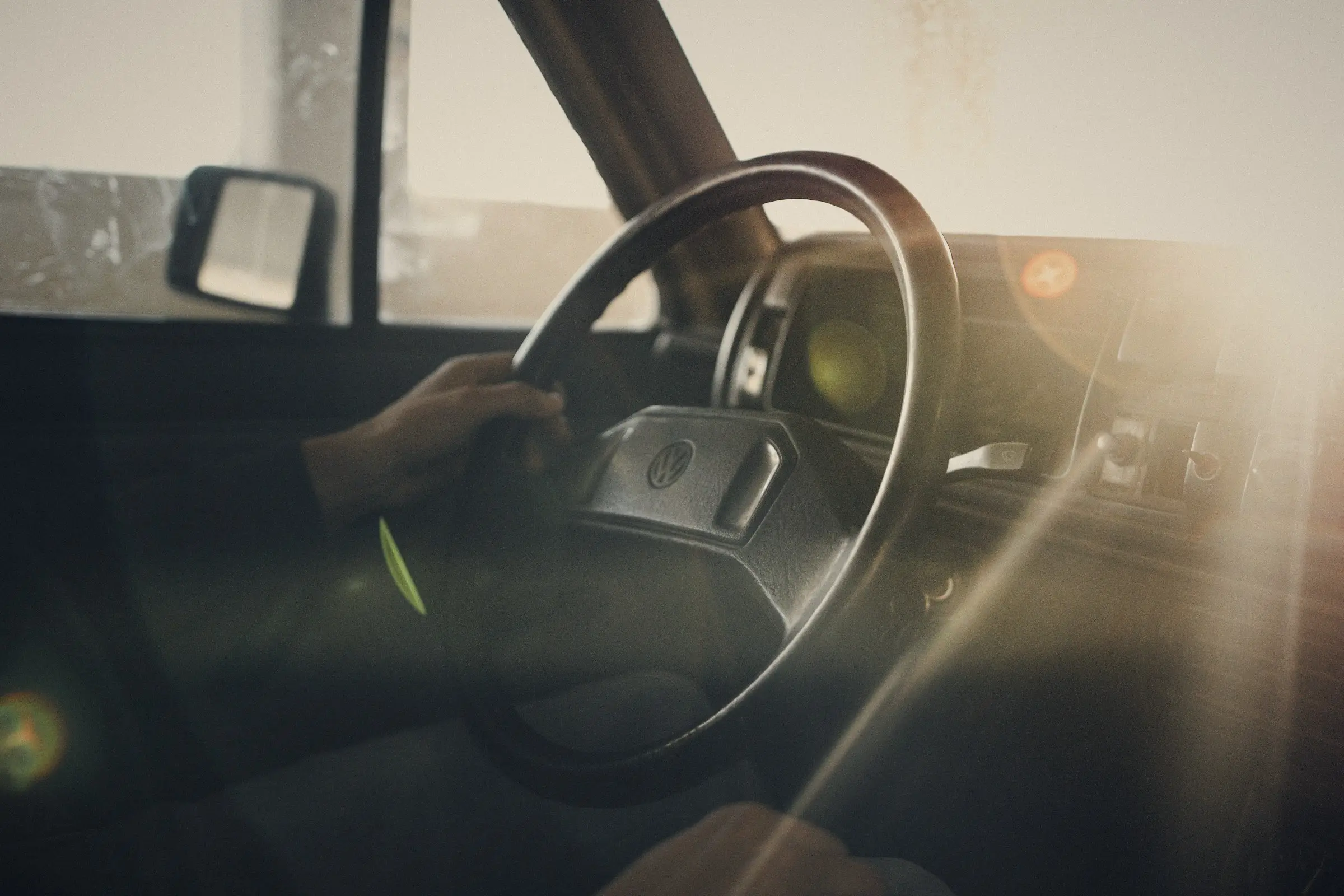 Manos sobre el volante de un carro con luz de atardecer