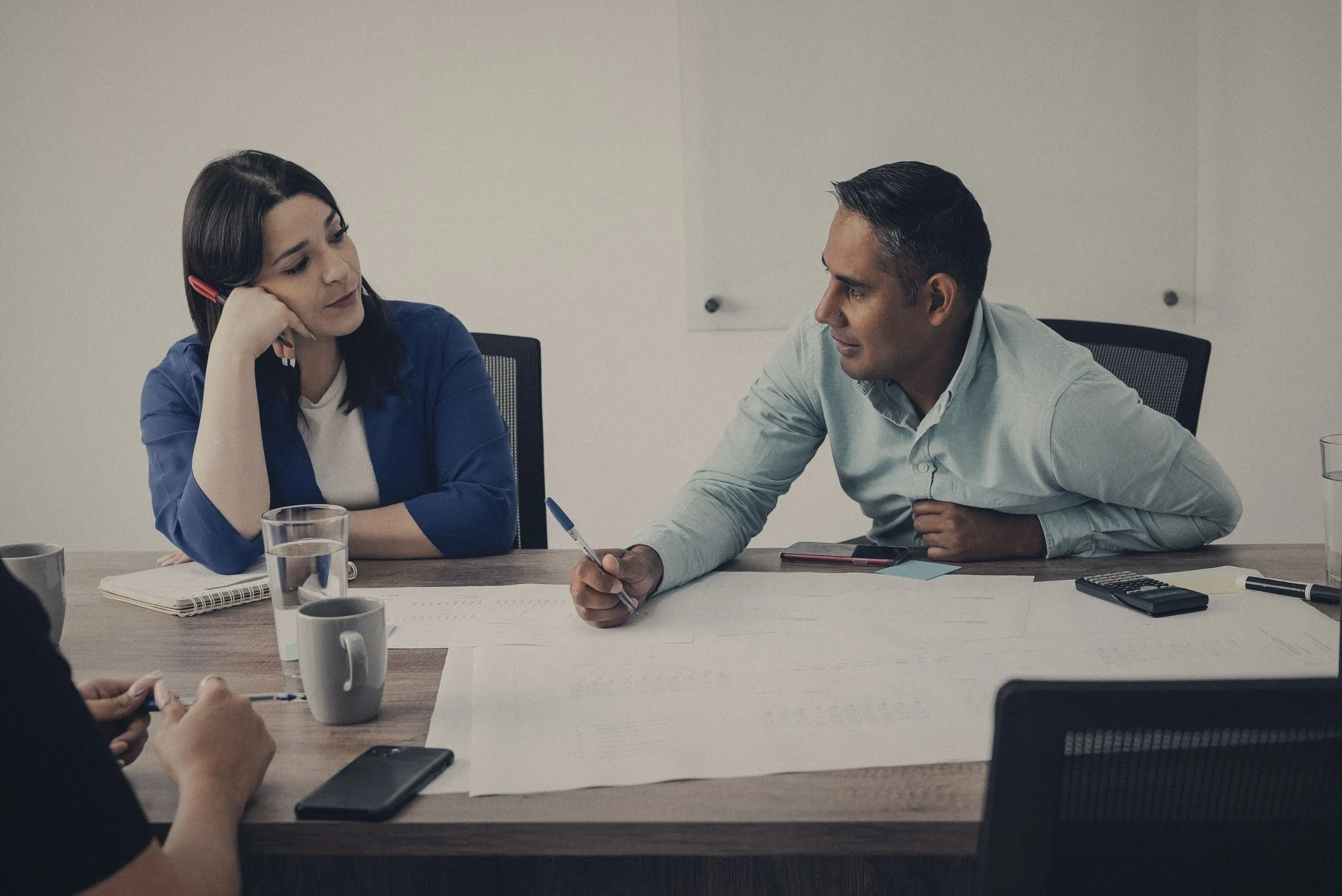 Dos profesionales conversando en una reunión de trabajo en una oficina