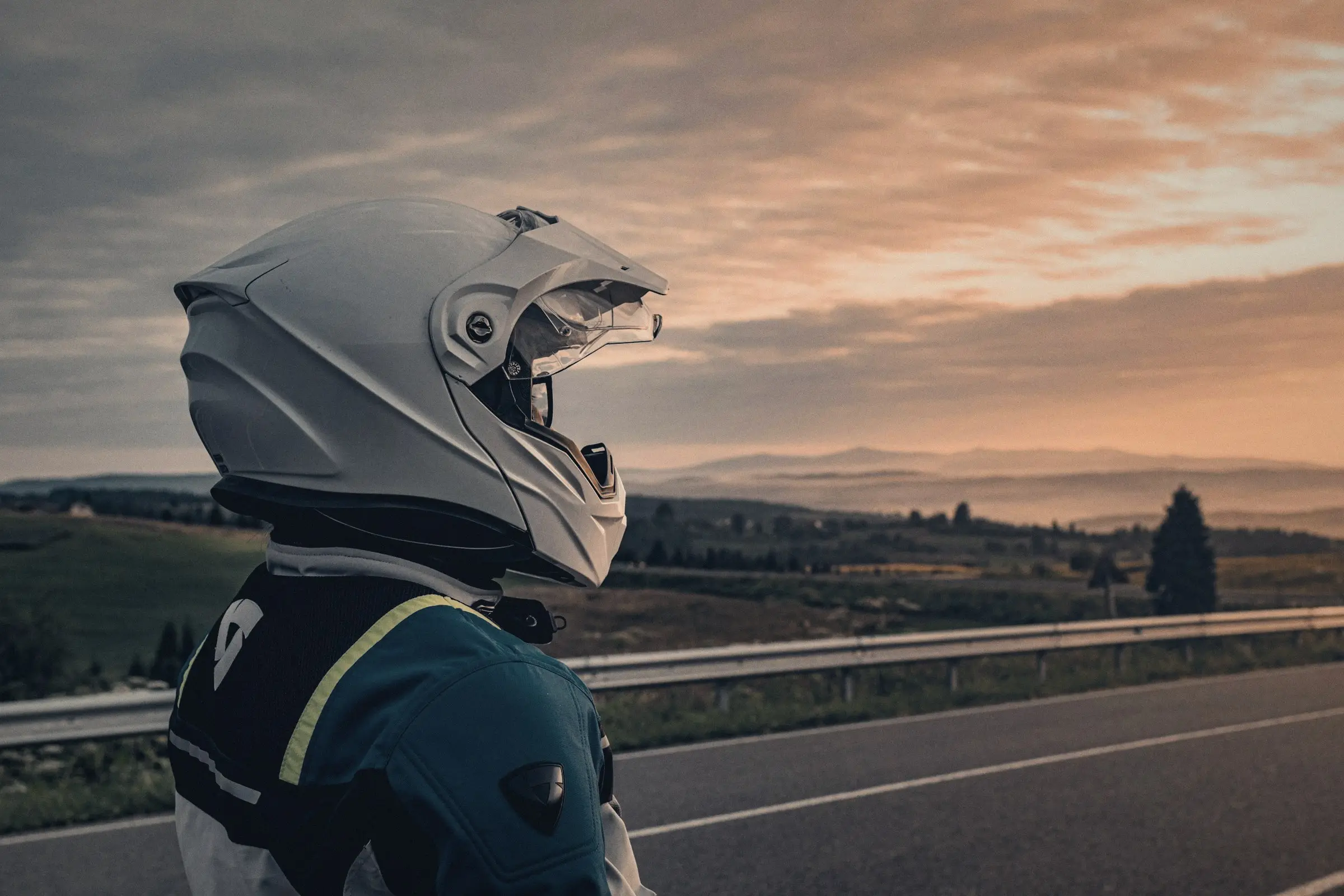 Motociclista con casco mirando la carretera al atardecer