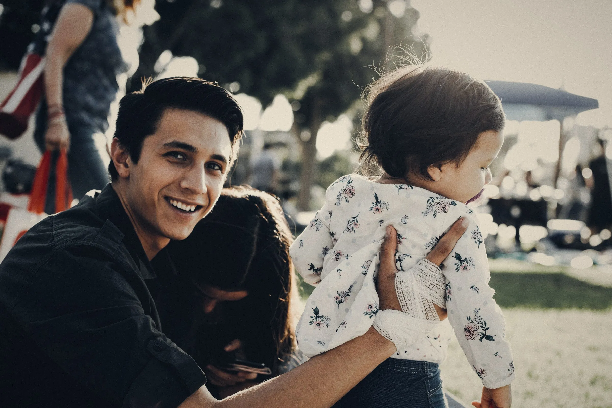 Padre joven sonriendo con su hija en brazos